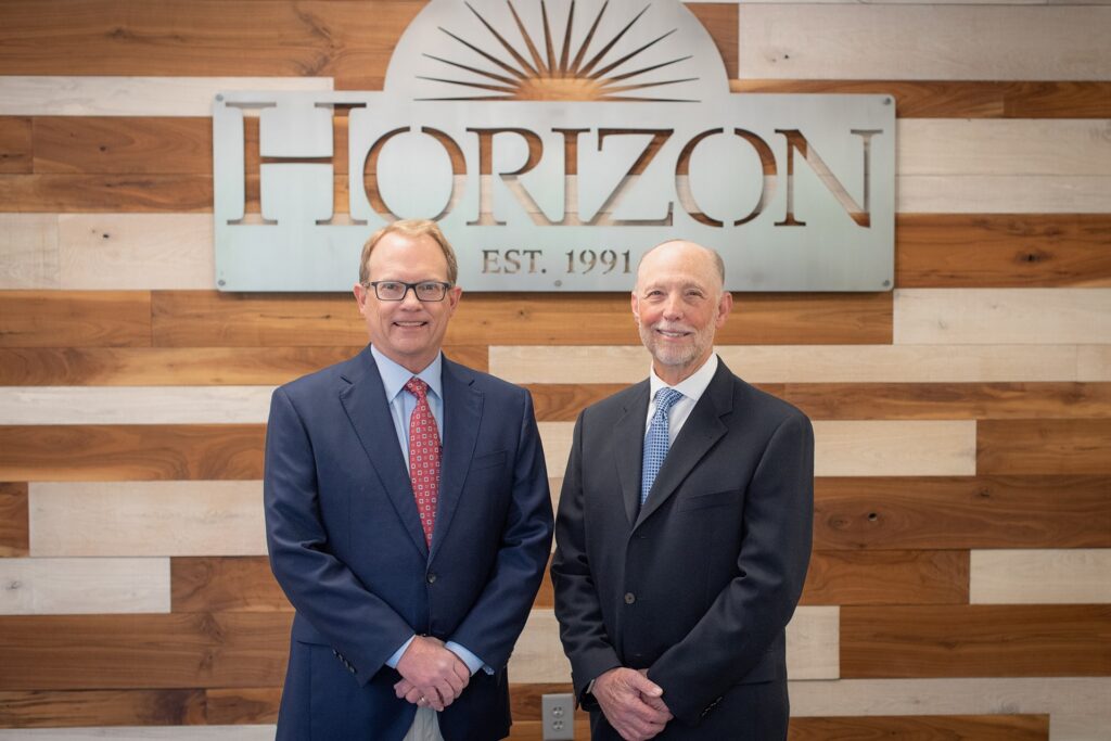 Founders Jeff and Steve in front of horizon logo on office wall